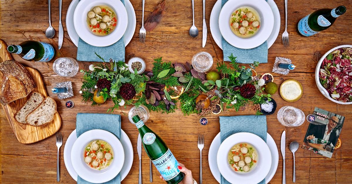 Photo of a dinner table featuring actor and filmmaker Stanley Tucci's S.Pellegrino 2023 recipe kit and bottles of S.Pellegrino water