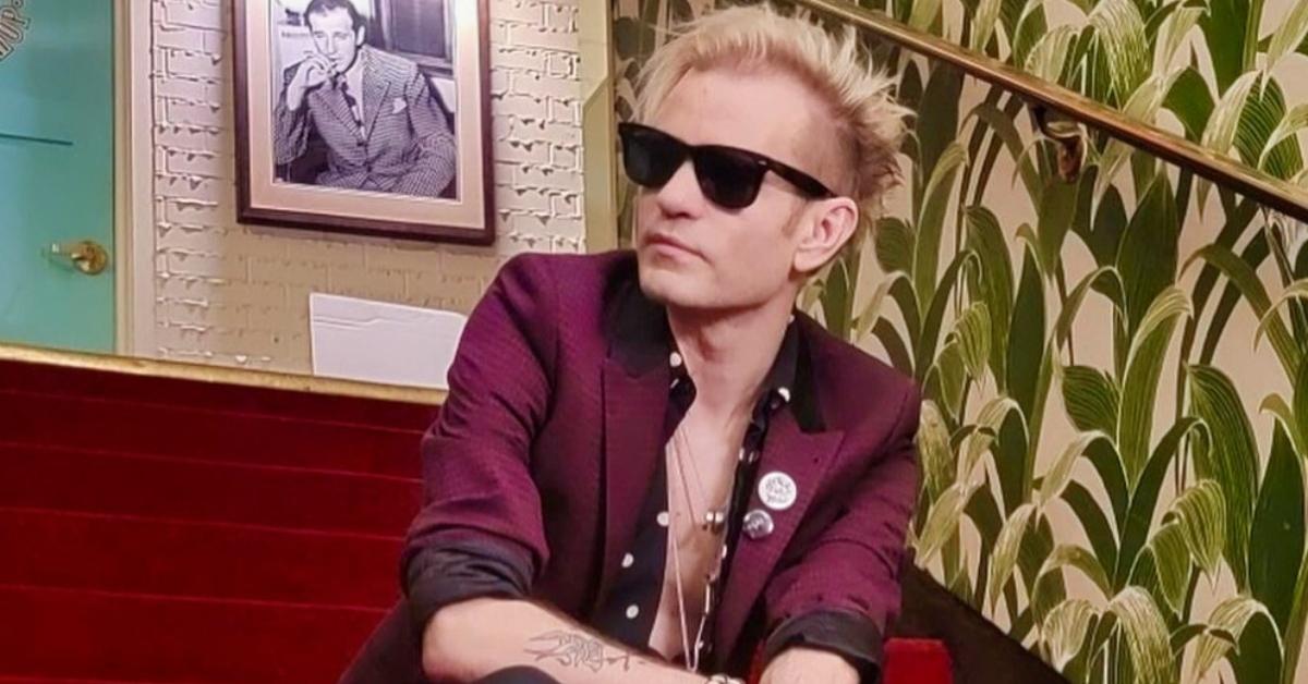 Deryck Whibley sits on red carpeted stairs