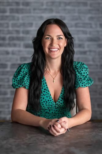 Melissa wears a v-neck dress in blue-green with polka dots and puff sleeves, smiling for her official portrait for Season 2 of 'The Mole.'