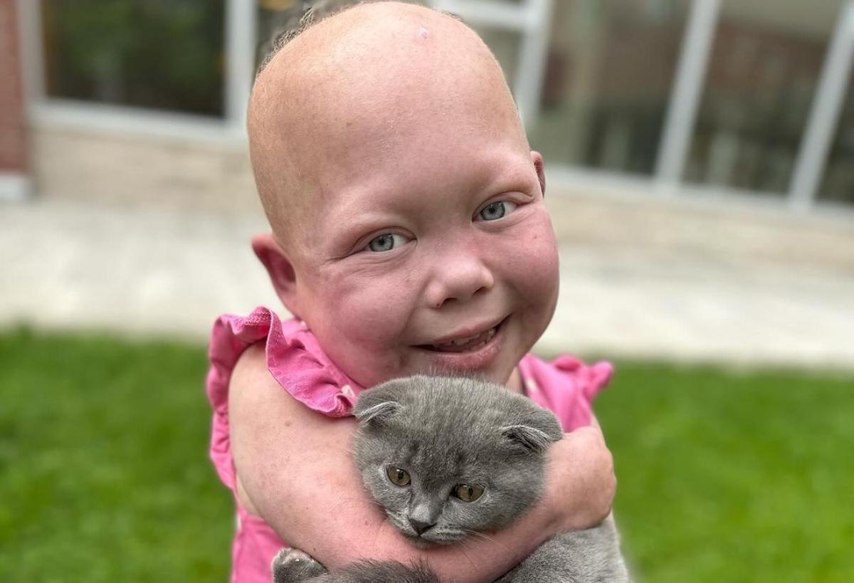 Bella Brave in a pink dress holding a cat