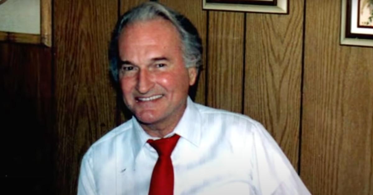 Ron Rudin smiles in front of a wood-paneled wall