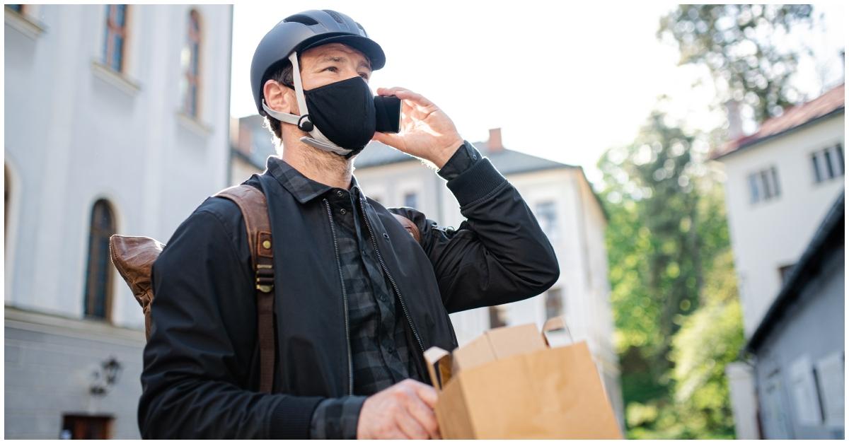 A delivery driver on his bike delivering food.