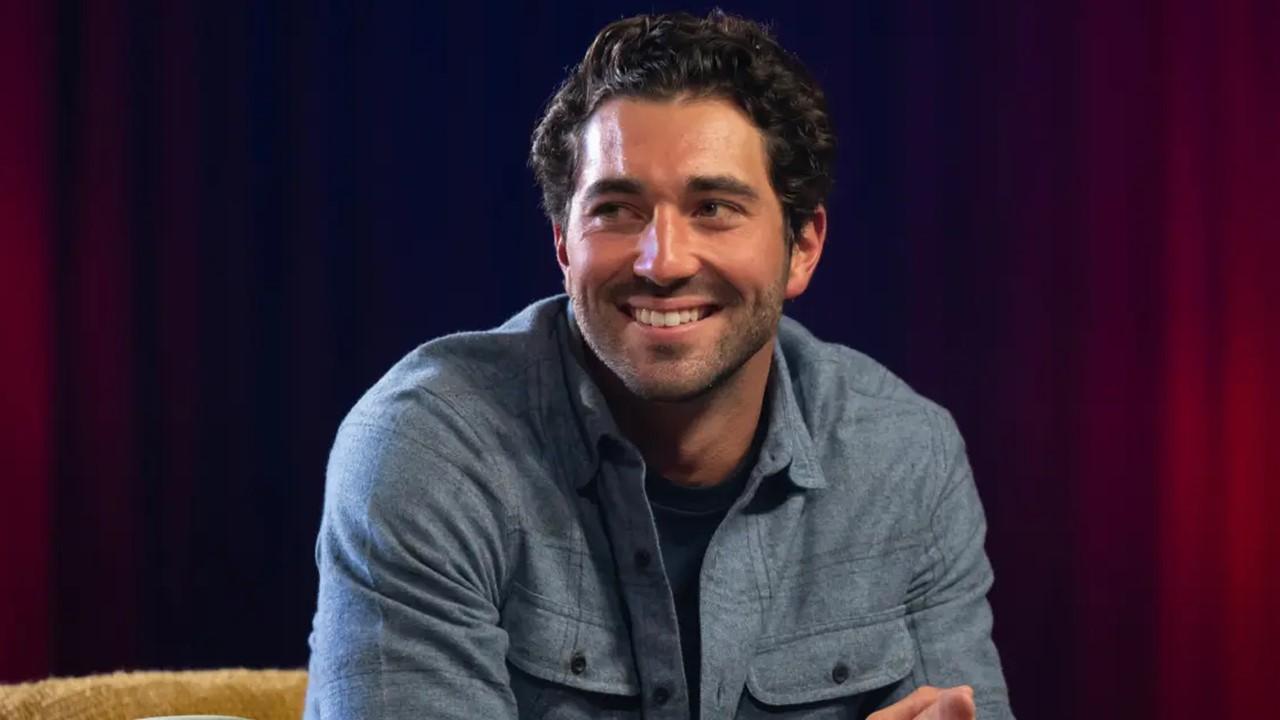 'The Bachelor' Season 28 lead Joey Graziadei sits and sports a grin while dressed in a cozy gray flannel utility shirt