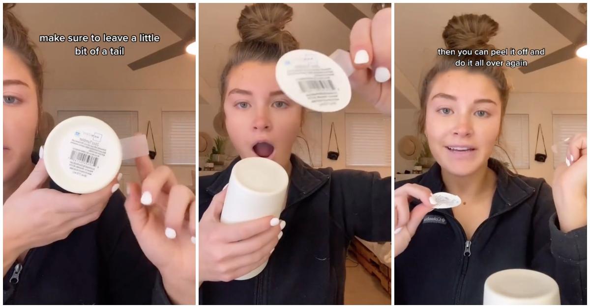 Woman looks shocked as she removes sticker adhesive tag with a piece of tape.