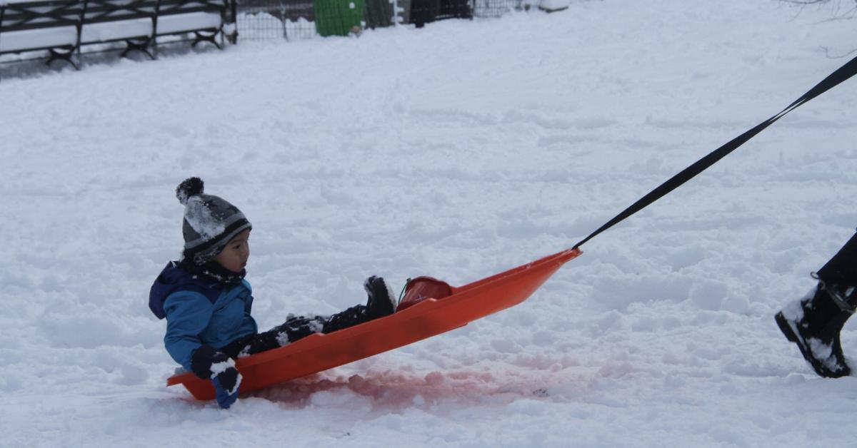 A little kid gets pulled on a sled in the snow in NYC in January 2022.