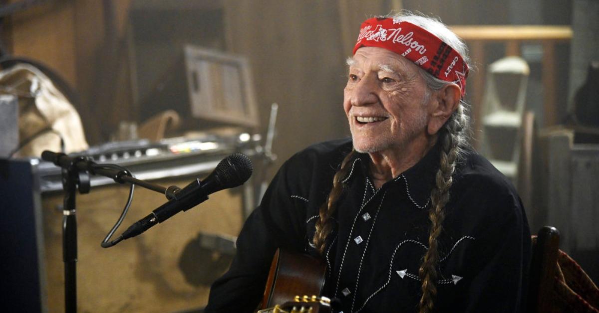 Willie Nelson preparing to sing with his guitar.