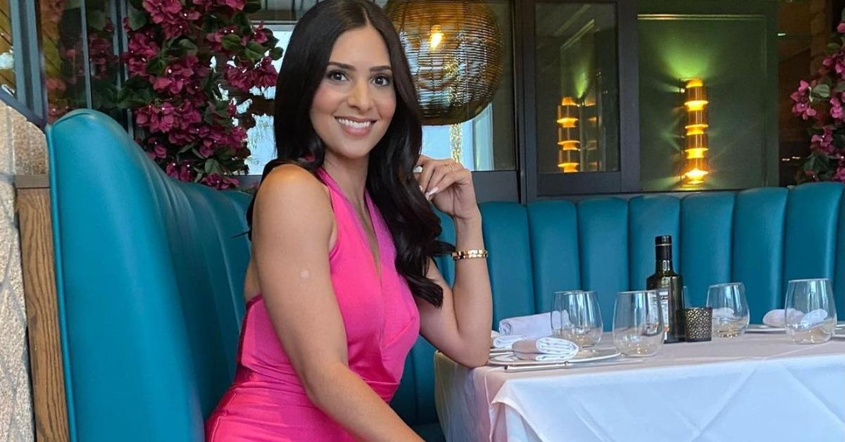 Camila Banus sits at a table in a pink dress