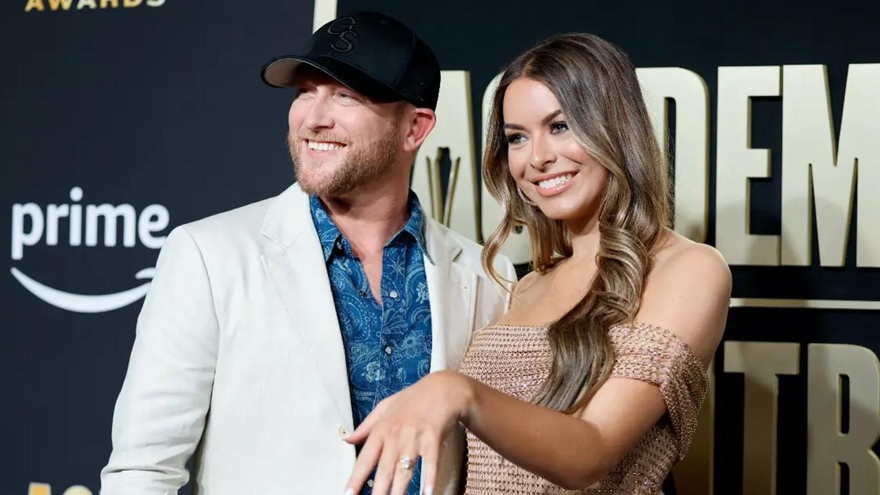 (L-R) Cole Swindell and Courtney Little, showing off her engagement ring, attend the ACM Awards in Frisco, TX 