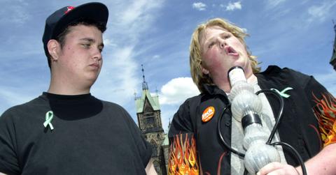 One young man looking distrurbed watching another young man smoke a bong.