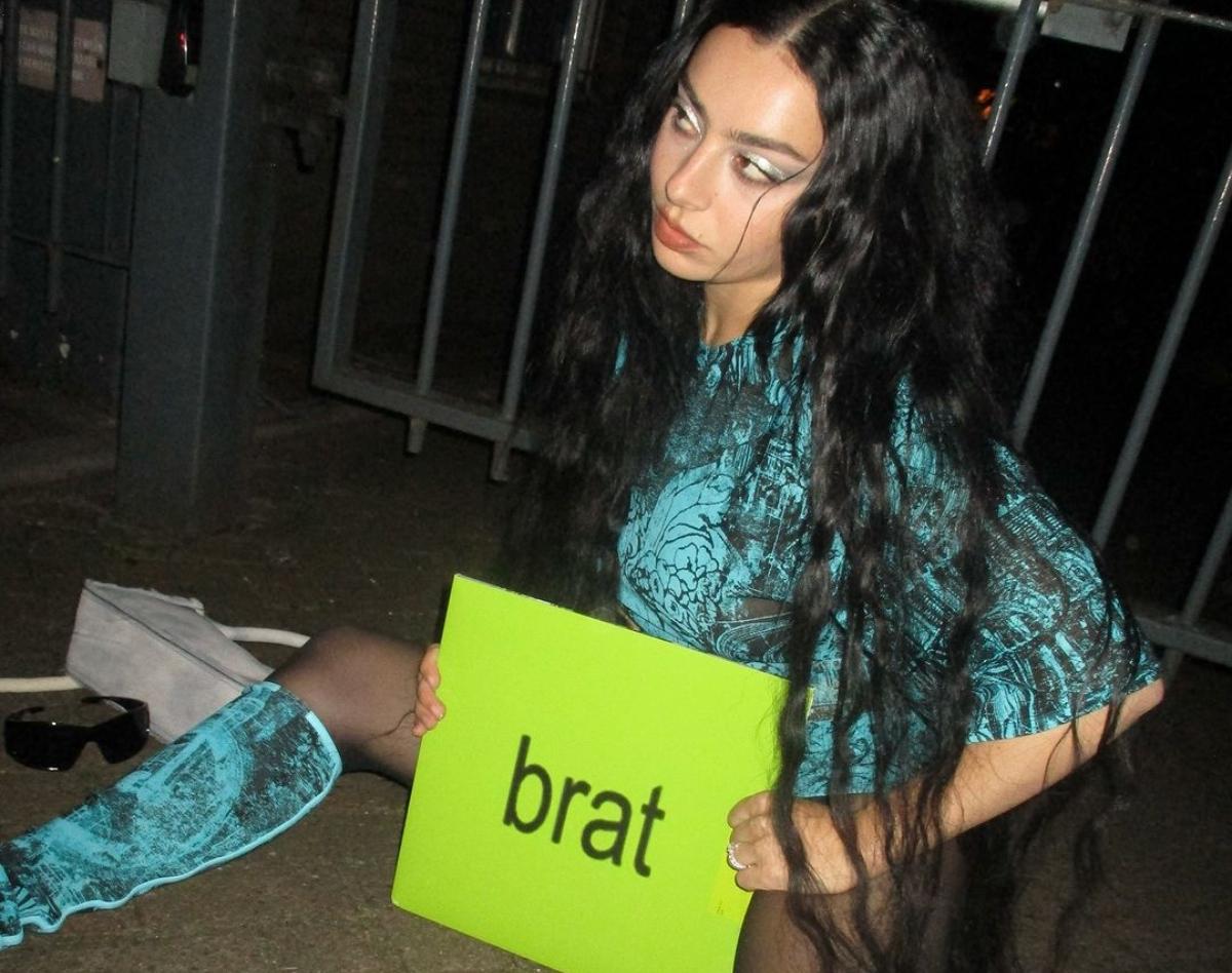 Charli XCX holding a "brat" sign