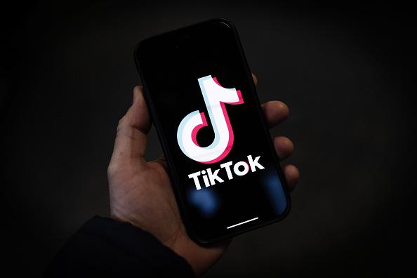 Person holding phone displaying TikTok logo