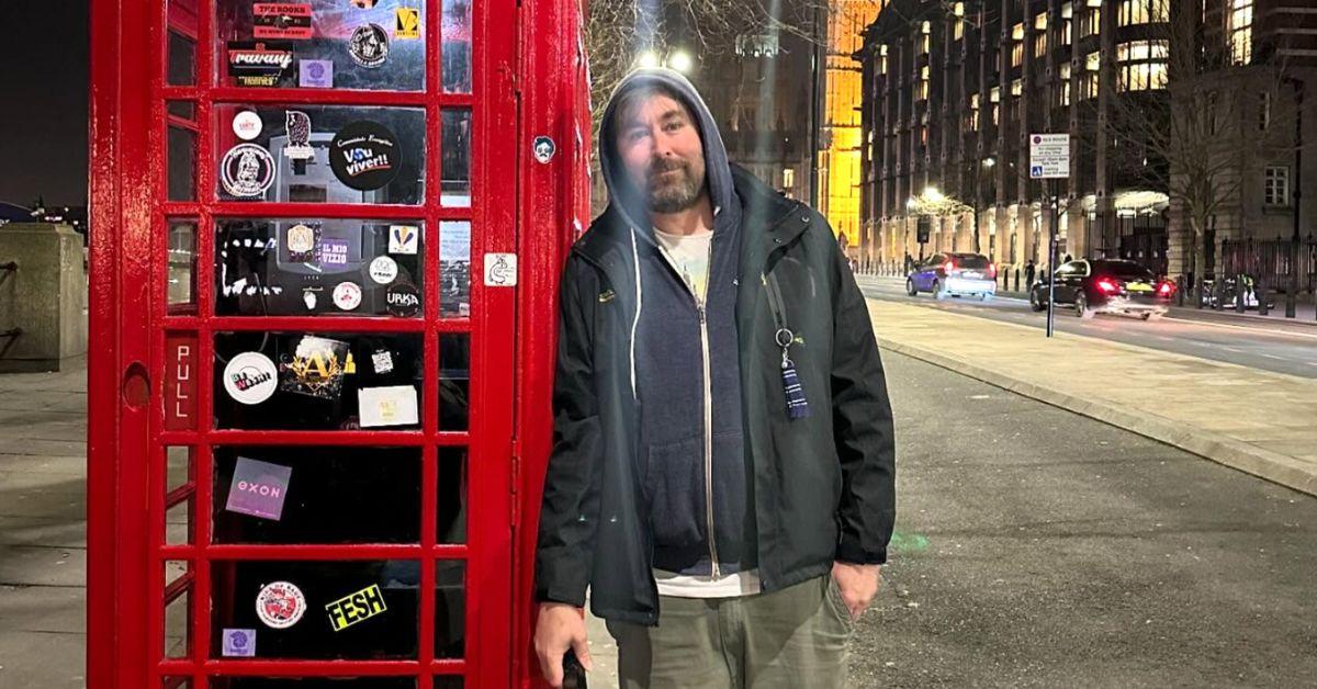 Adam the Woo leaning against a telephone booth in London. 