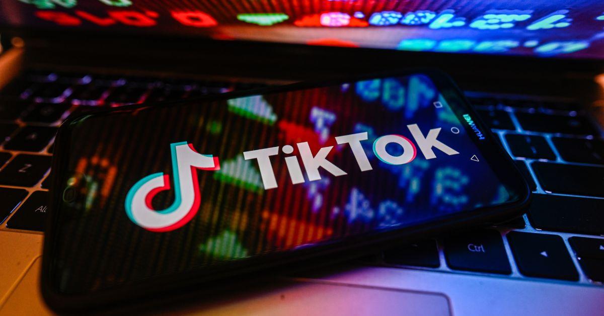 TikTok on an iPhone screen with reflections from laptop
