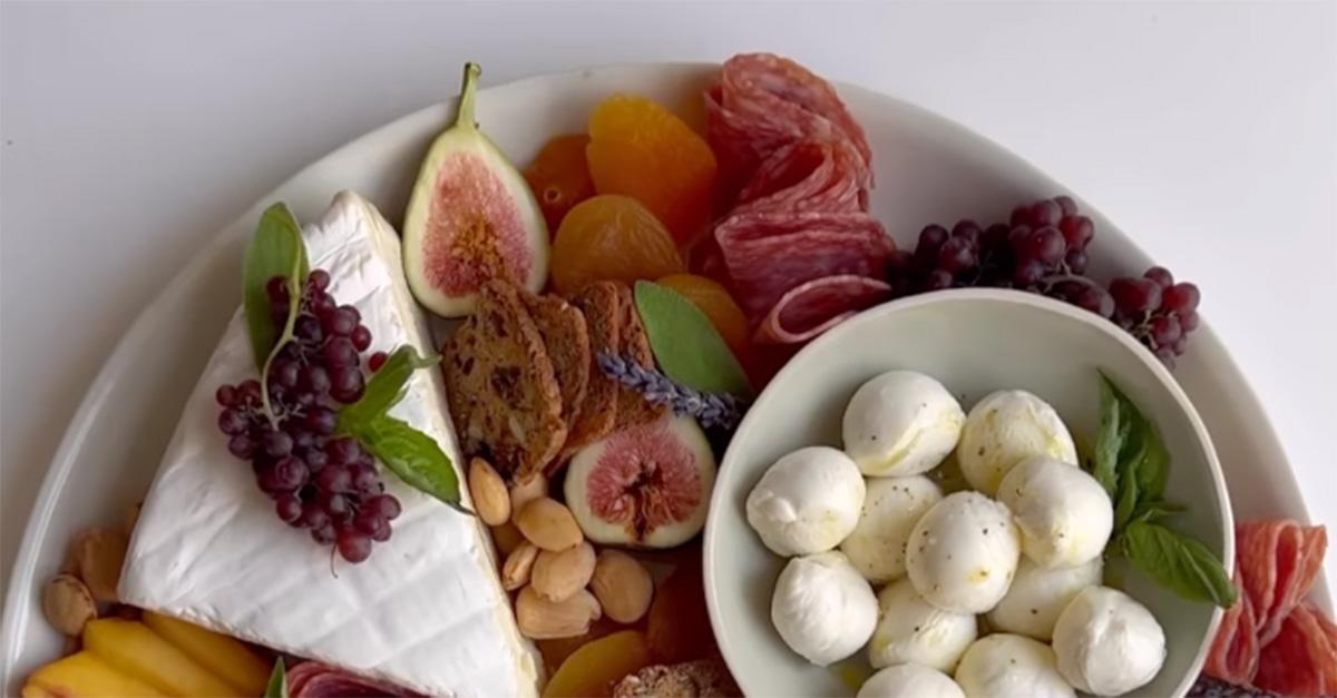 A "girl dinner" featuring nuts, cheeses, grapes, and some sliced meat. 