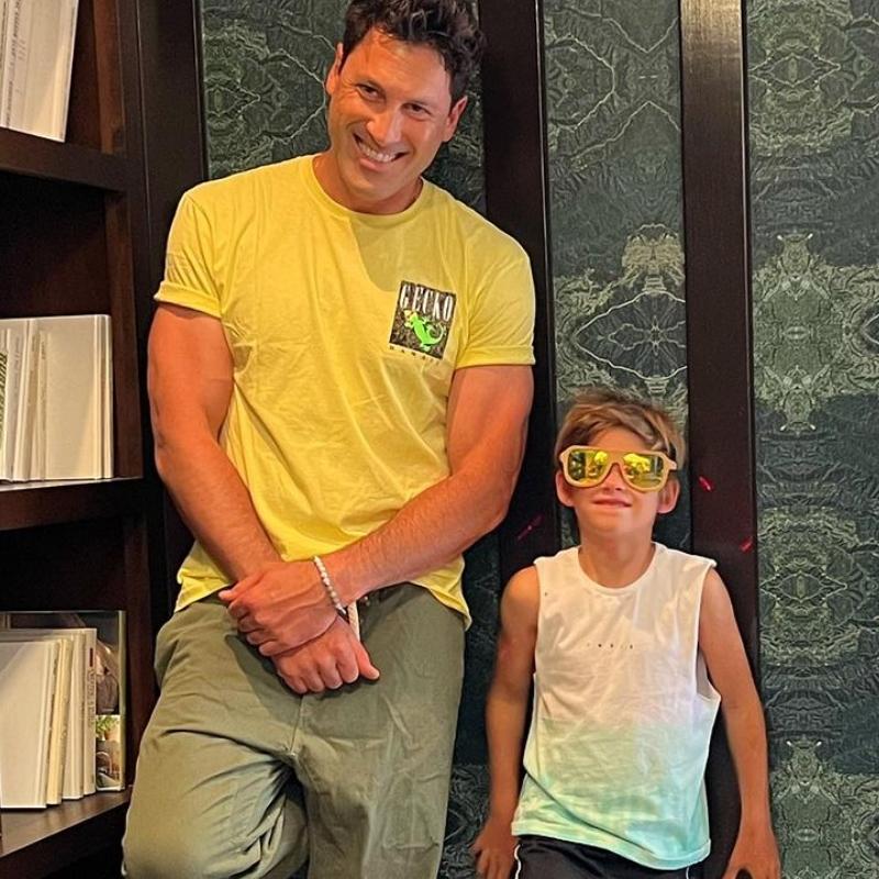 Maks Chmerkovskiy and his son standing against a wall