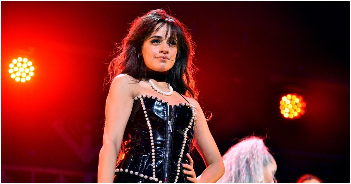 Camila Cabello performing onstage with her hand on her hip.