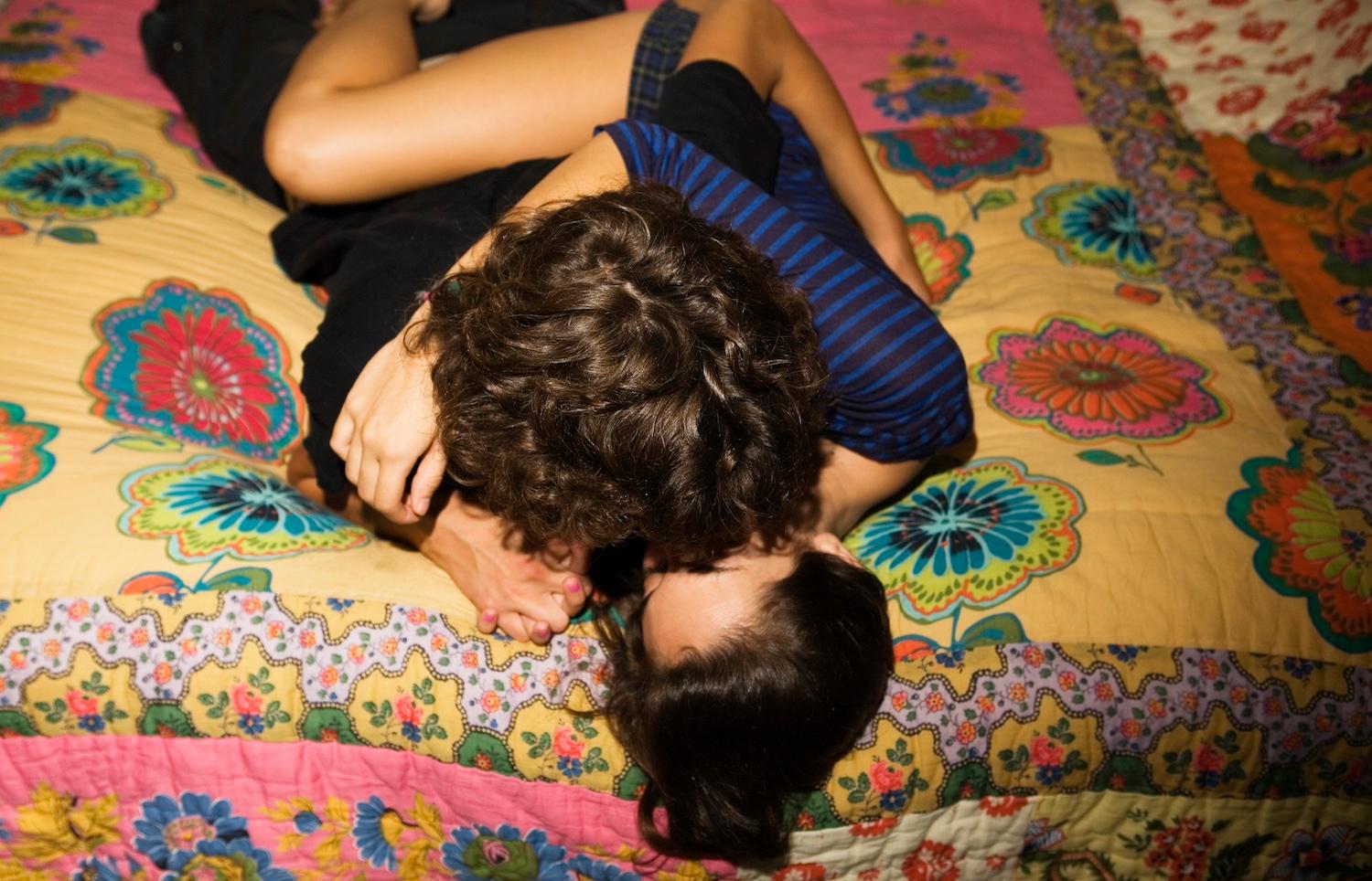 A teenage couple snuggling on a bed