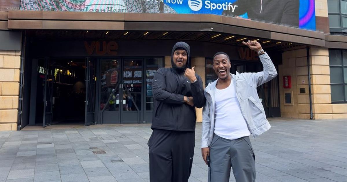 Yung Filly pointing at a marquee with his podcast on it alongside Chunkz. 