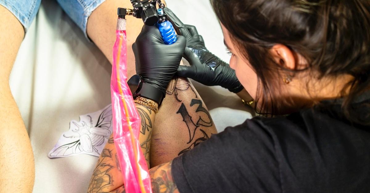A tattoo artist doing work on a leg