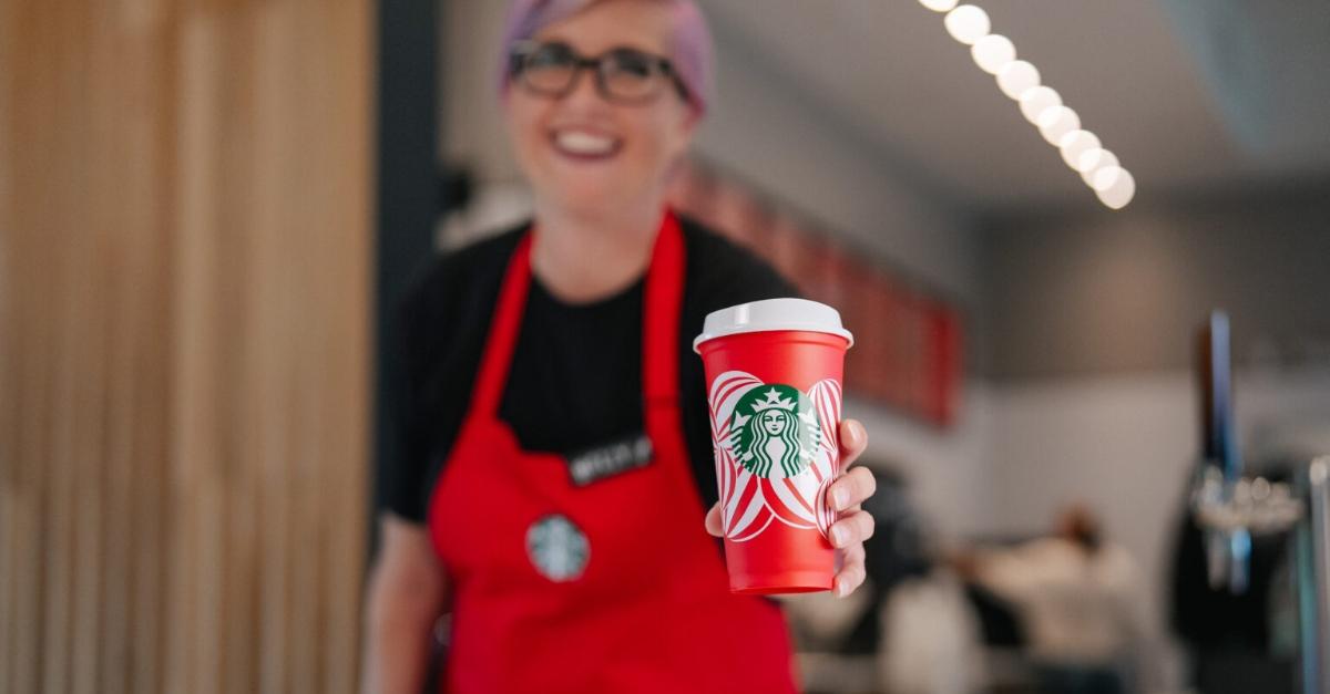 A Starbucks employee holding the free reusable red cup.