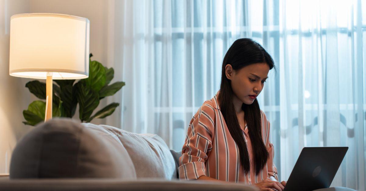 A woman typing on her laptop while sitting on her couch.