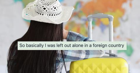 Woman sits with her back in white hat and suitcase and looks at map of world - stock photo