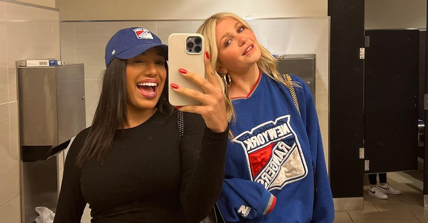 Jaz and Halley Kate wear New York rangers gear and take a mirror selfie in the background.