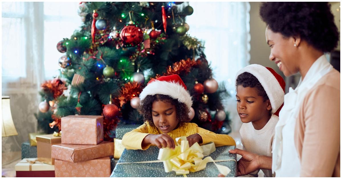 (l-r): Kids opening a present while a woman watches them