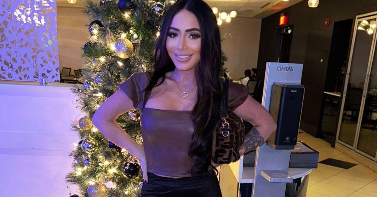 Angelina Pivarnick poses for a photo in front of a Christmas tree