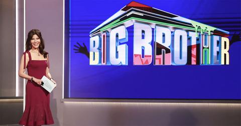 Julie Chen in a red dress with a screen that says Big Brother.