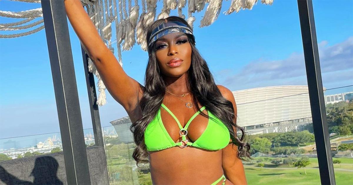 Quad Webb in a green bikini with windows behind her. 