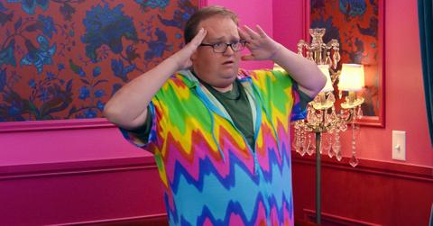 Brandon, in a green t-shirt and rainbow jumper, looks stressed with his hands on his temples during 'The Circle' Season 6.