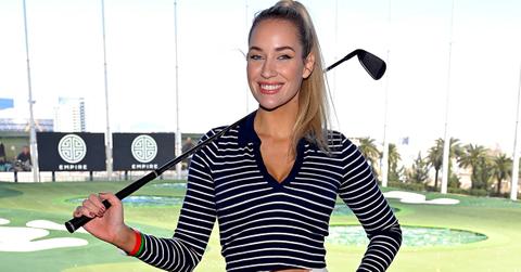 Paige Spiranac holding a golf club at a golf course.