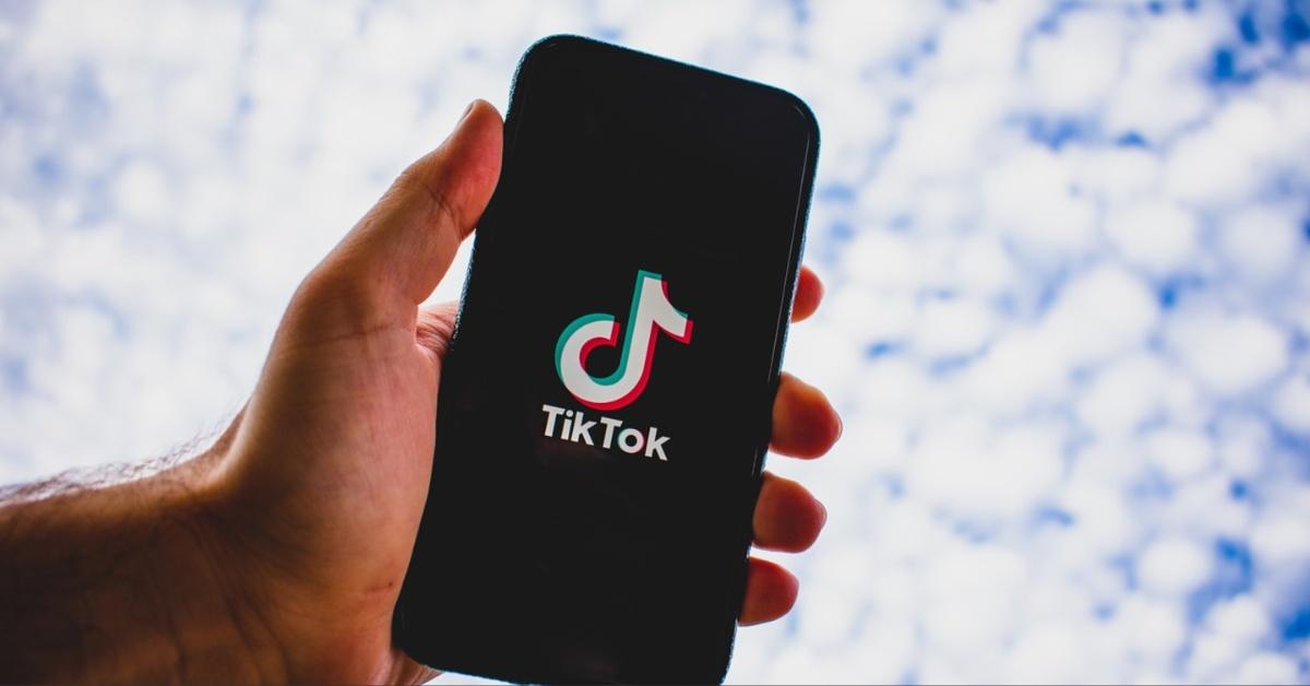 A hand holding a phone loading TikTok