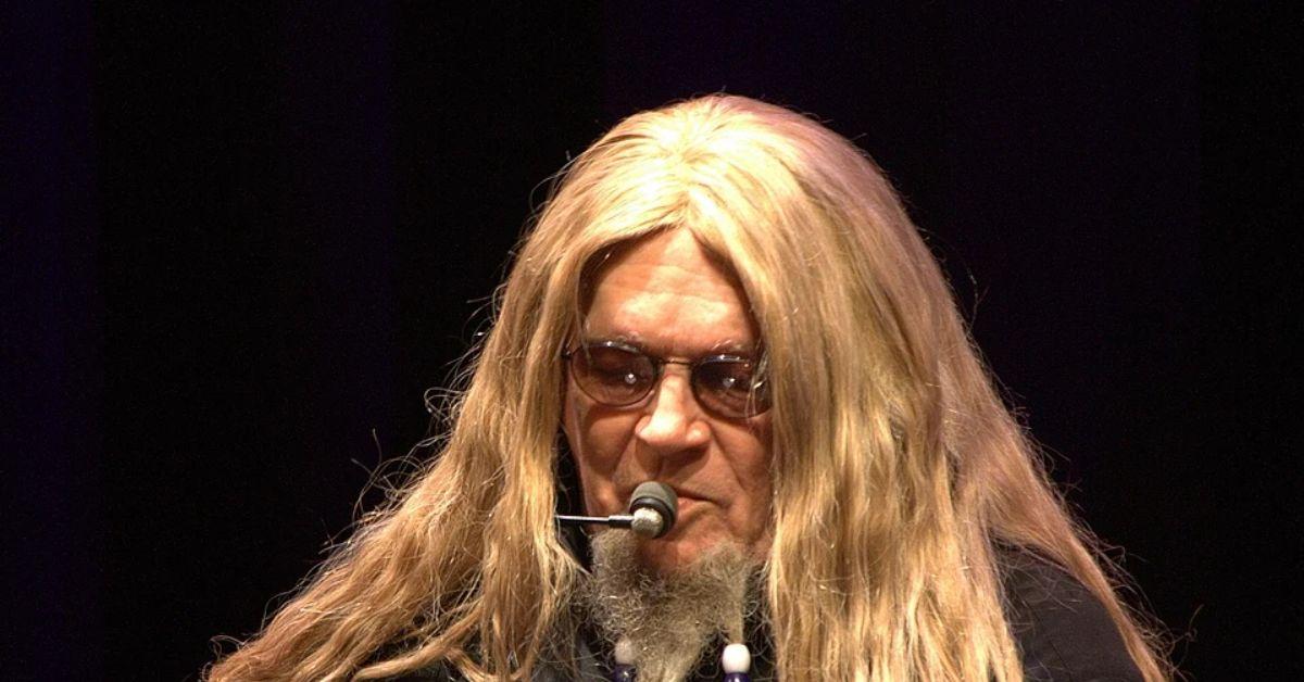 David Allan Coe singing into a mic on stage in 2011. 