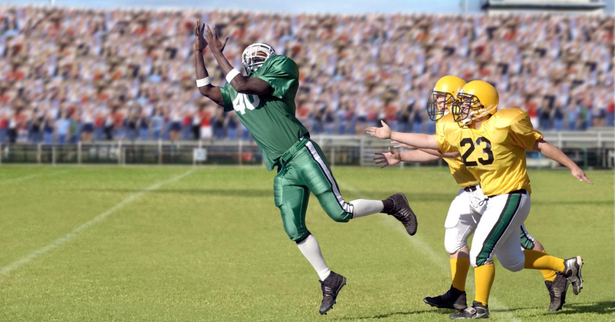 Football player attempts to catch the ball.