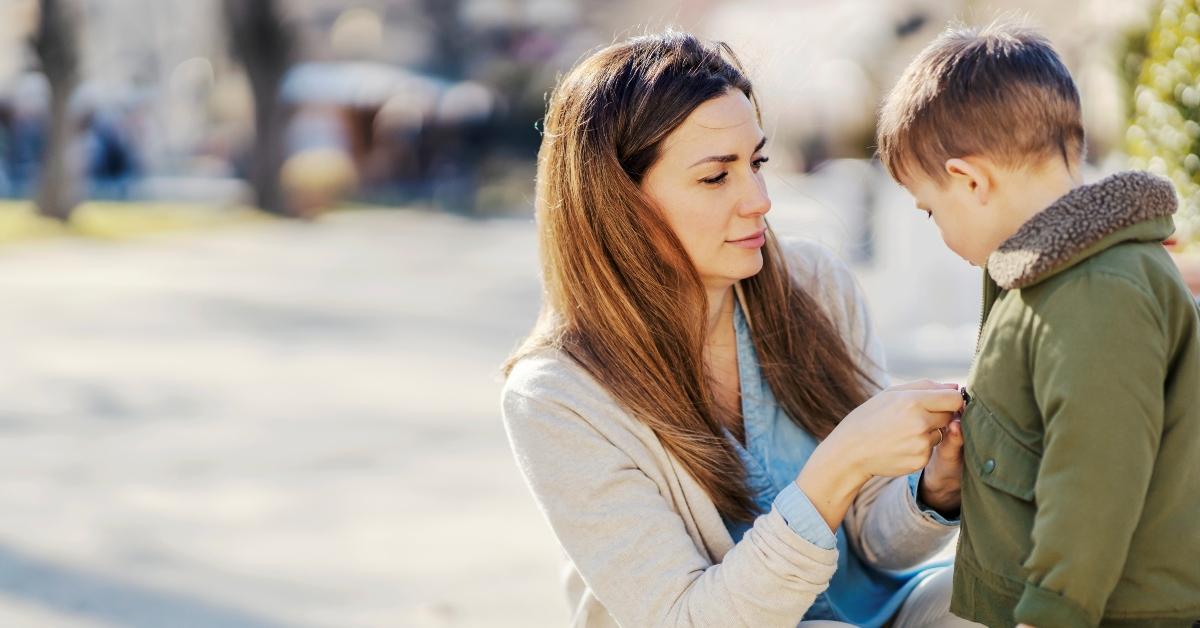 mom zips up son's jacket outside