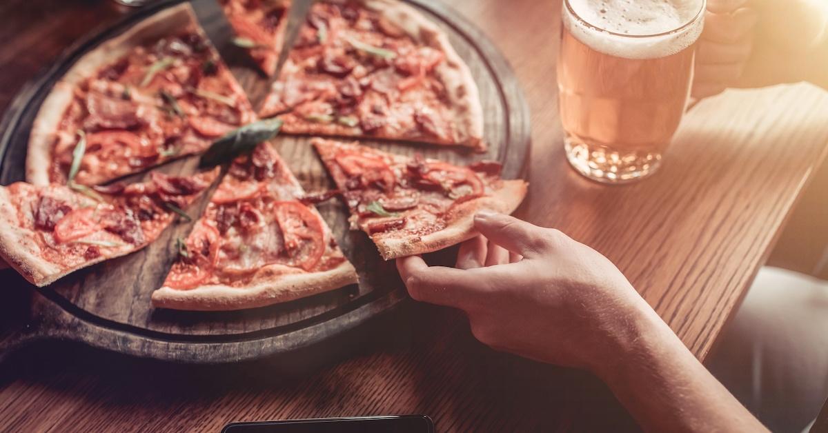 A person enjoying pizza and a beer