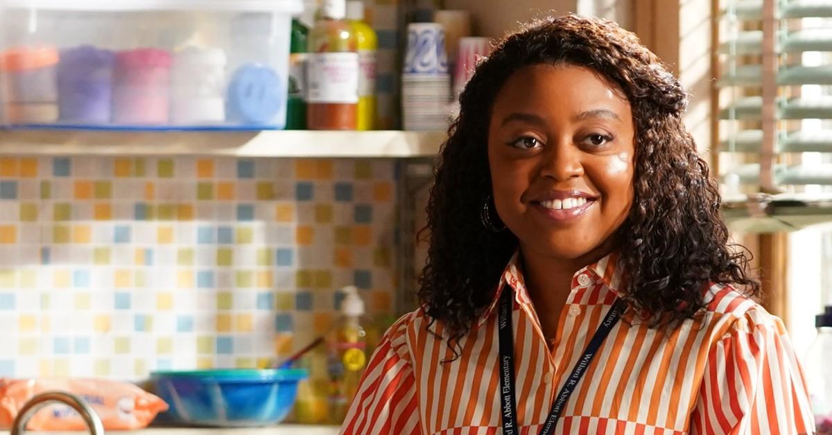 Janine (Quinta Brunson) in a red striped shirt, smiles in her classroom 