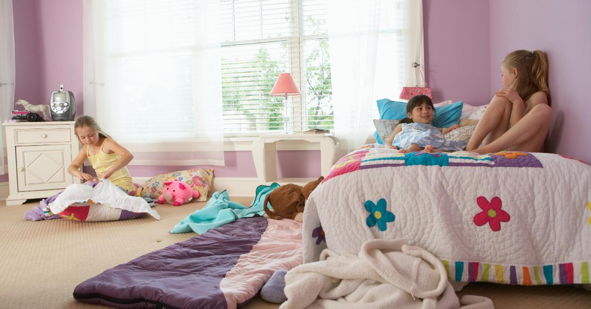 Three young girls sitting around and talking in a bedroom.