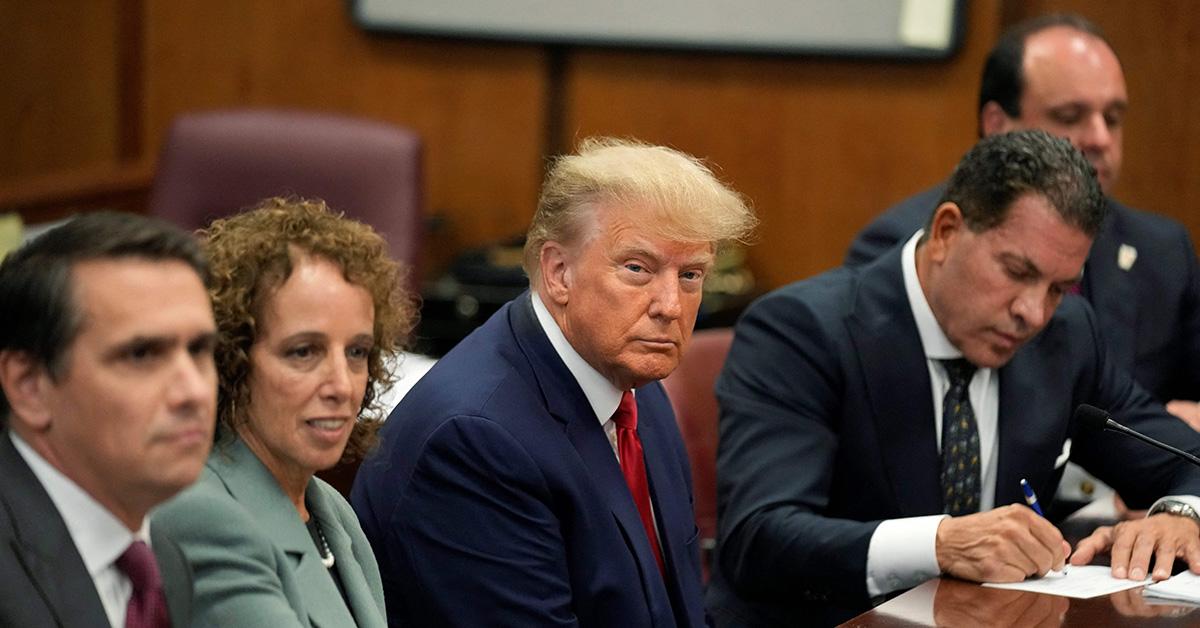 Donald Trump sitting in a courtroom surrounded by attorneys. 