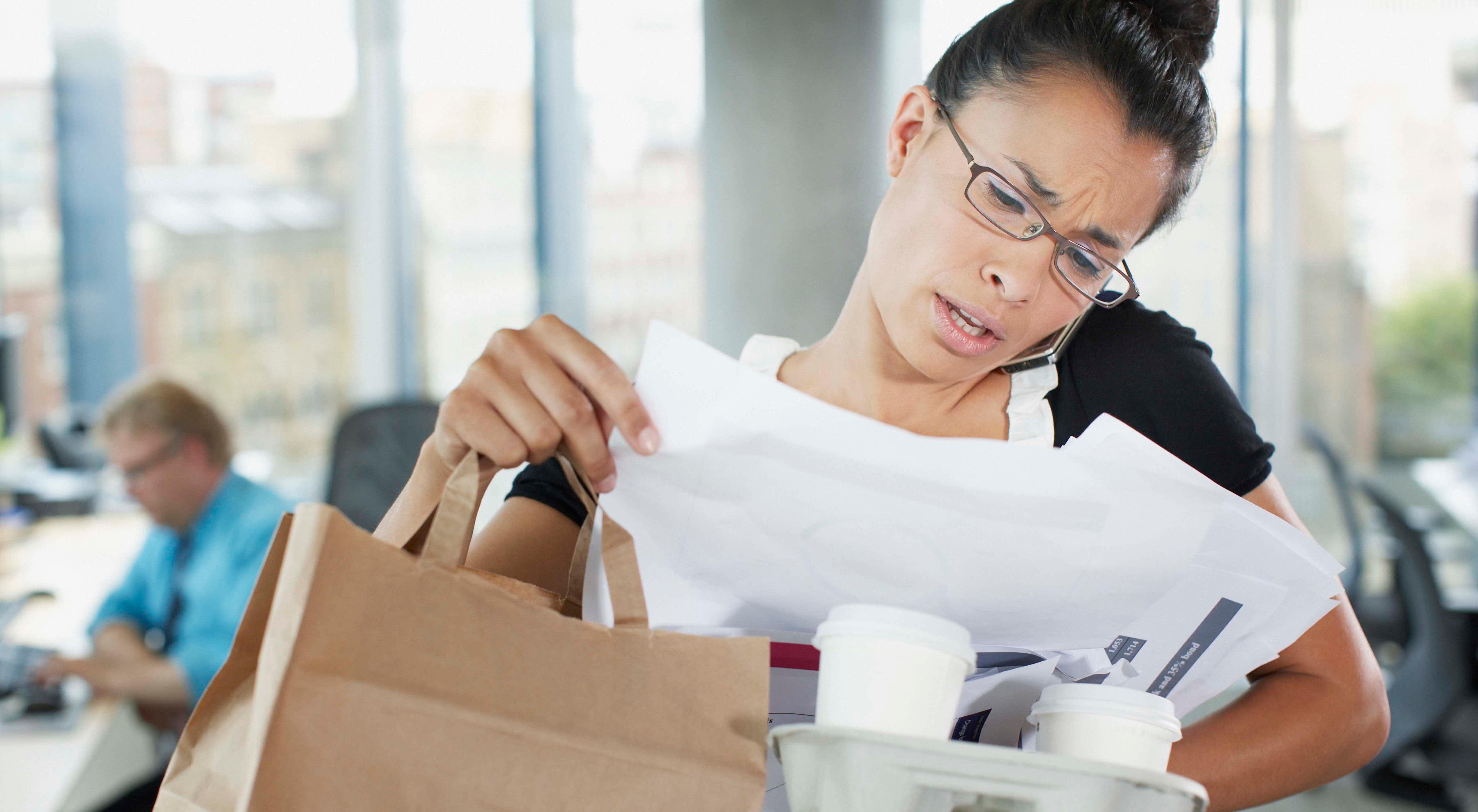 A business woman tries to do multiple things at once while at work.