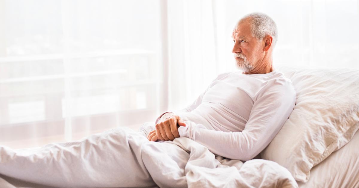 Grumpy old man lays in bed.