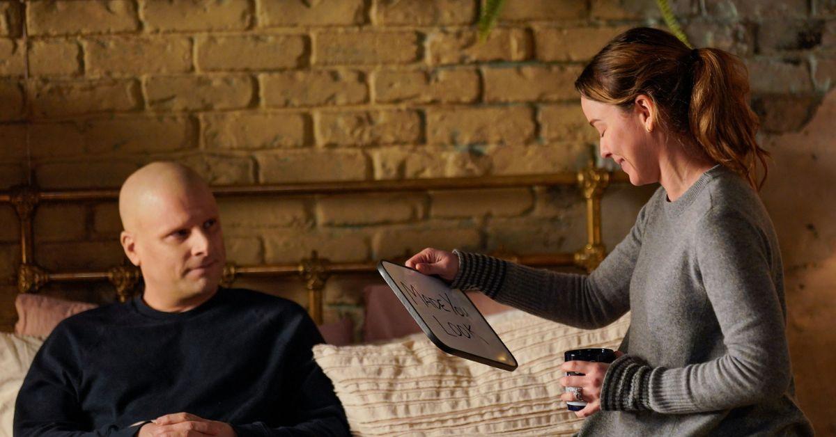 (l-r): James Roday Rodriguez as Gary smiling at Allison Miller as Maggie holding a whiteboard and tea