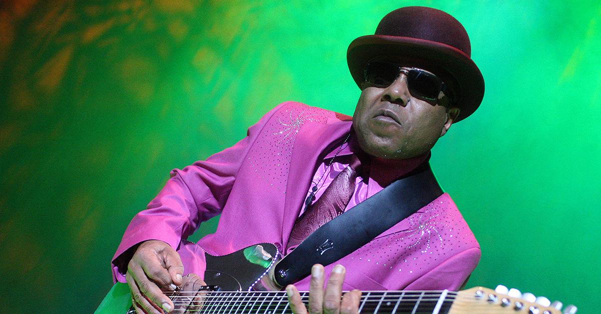 Tito Jackson performing on stage in a pink suit in 2009. 