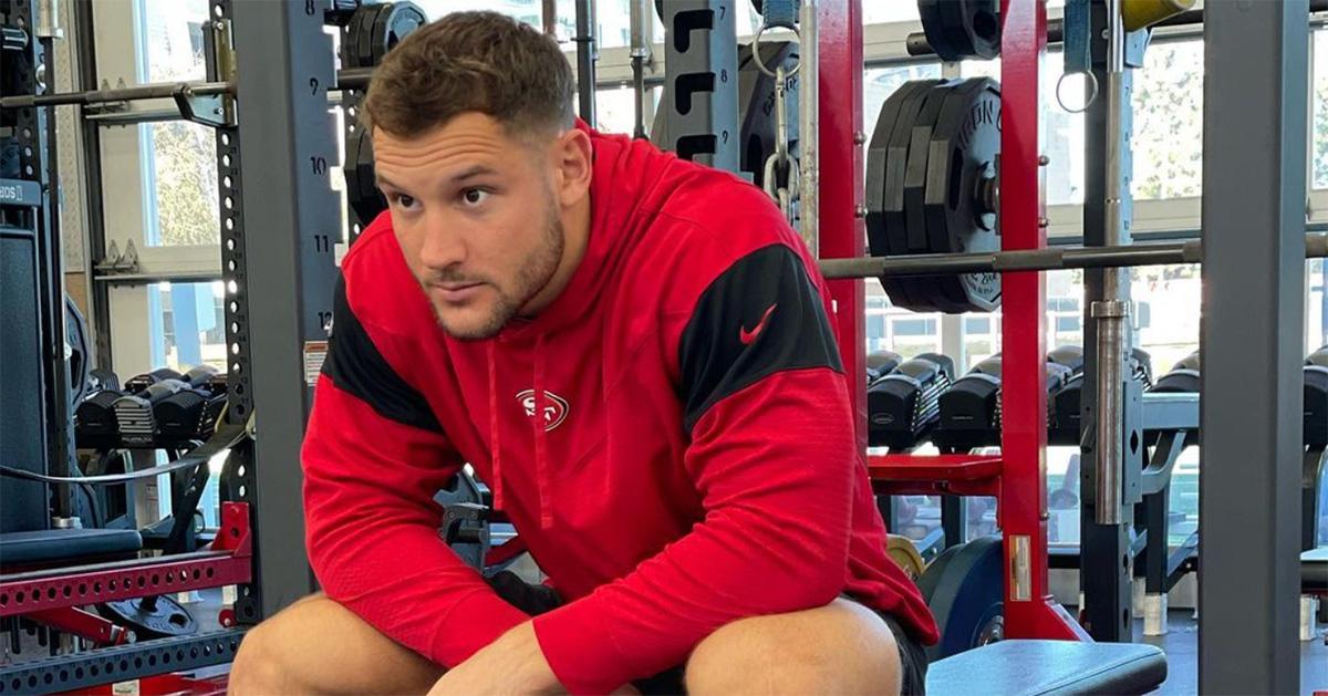 Nick Bosa in a 49ers hoodie lifting weights. 