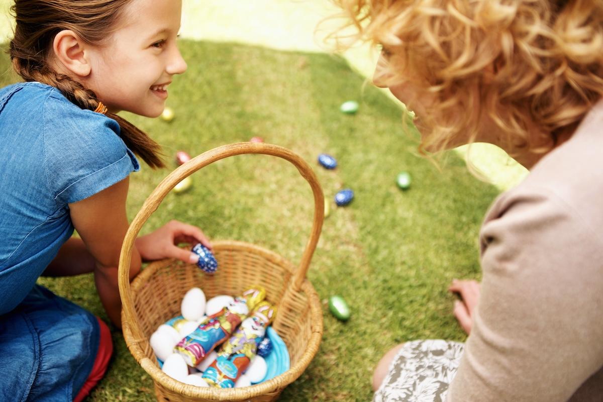 A young girl picking up Easter eggs and chocolate