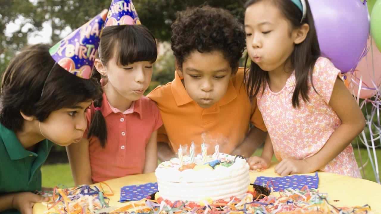 Kids blowing out candles on a birthday cake