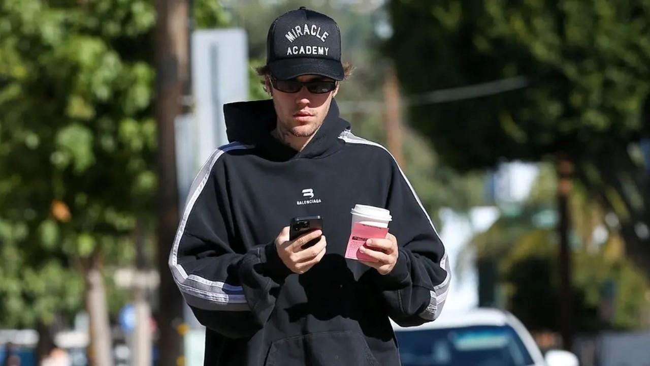 Justin Bieber holding a coffee and his phone