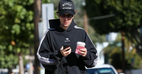 Justin Bieber holding a coffee and his phone